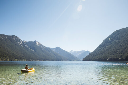 Rear view of man paddling inflatable boat on Chilliwack Lake.