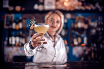 Charismatic girl tapster creates a cocktail on the bar