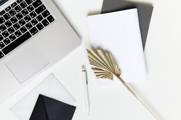 workspace with laptop white and gray notepad and palm leaf and phone. two notepads lie on a plain background with a pen. business concept for meeting in boho style. space for writing in the style