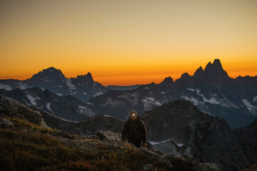 Hiker travels by headlamp on mountain ridge after sunet.
