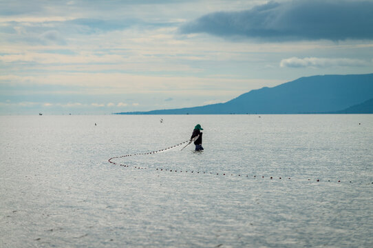 Fisherman lays net in the shallow waters of the sea. Kampot province, Cambodia.