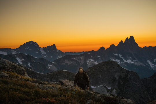 Hiker travels by headlamp on mountain ridge after sunet.
