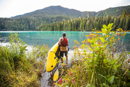 Man carries inflatable packraft (kayak) into Cheakamus Lake, Whistler.