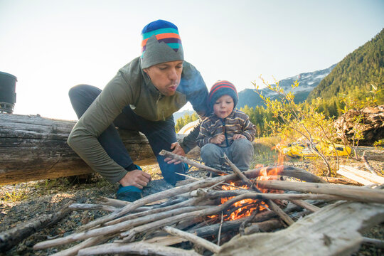 Father and son work together to start a fire at wilderness campsite.