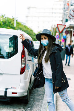 Young Woman In The City Wearing Face Mask And Hailing A Taxi Cab