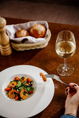 Fresh salad plate with shrimp, tomato and mixed greens on wooden background close up. Healthy food. Clean eating.