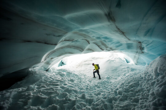 Backpacker explores the inside a glacial ice cave.