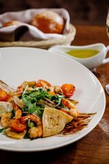 Fresh salad plate with shrimp, tomato and mixed greens on wooden background close up. Healthy food. Clean eating.