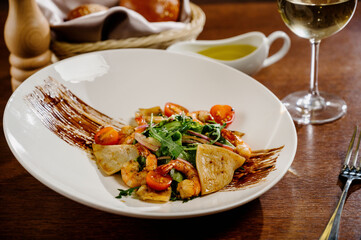 Fresh salad plate with shrimp, tomato and mixed greens on wooden background close up. Healthy food. Clean eating.