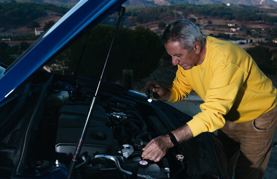 Elderly traveler with flashlight opening the trunk of the vehicle