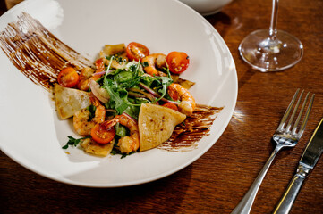 Fresh salad plate with shrimp, tomato and mixed greens on wooden background close up. Healthy food. Clean eating.