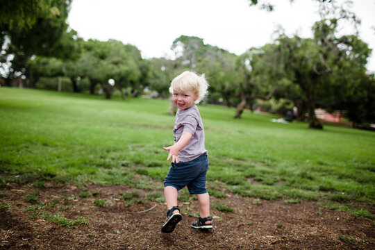 Two Year Old Looking Back at Camera While Running Through Park