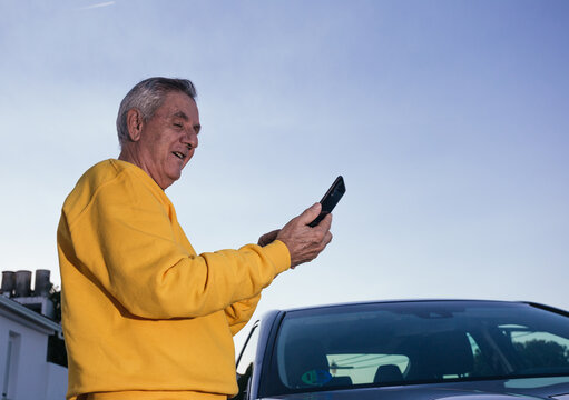 Elderly traveler using the GPS of his smartphone near the car