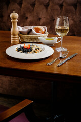 Black spaghetti. Spicy Black seafood pasta with squid with basil on wooden table.