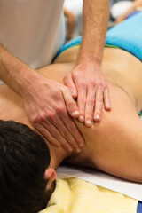 A masseur performs a back massage on a patient