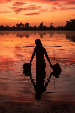SRA SRANG,ANGKOR PARK, SIEM REAP, CAMBODIA - 17 August 2014: Local lady collects water in buckets over the shoulder for her garden from angkorian bathing pool.