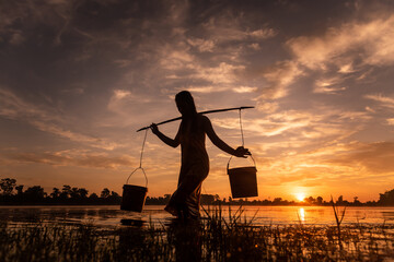 SRA SRANG,ANGKOR PARK, SIEM REAP, CAMBODIA - 17 August 2014: Local lady collects water in buckets over the shoulder for her garden from angkorian bathing pool.