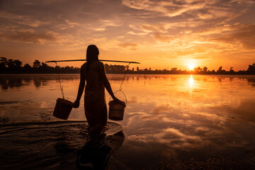 SRA SRANG,ANGKOR PARK, SIEM REAP, CAMBODIA - 17 August 2014: Local lady collects water in buckets over the shoulder for her garden from angkorian bathing pool.