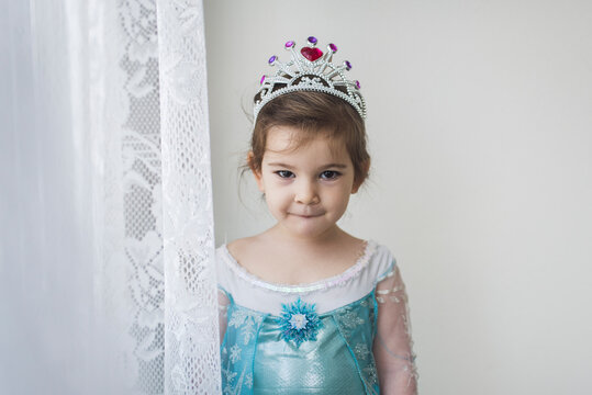 4 yr old in princess gown standing by lace curtain wearing tiara