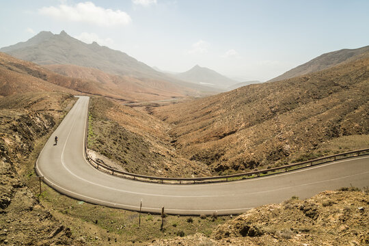 Panoramic view of winding road with cyclists at Astronomical Viewpoint of Sicasumbre, Fuerteventura, Spain.