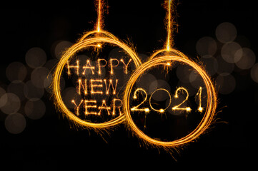 Long exposure photo written Happy new year 2021 text with Sparkle in bulb fireworks combined on gold unfocused light background