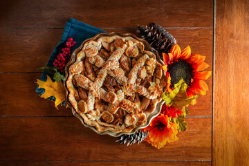 apple pie decorated with fall seasonal props on a kitchen table