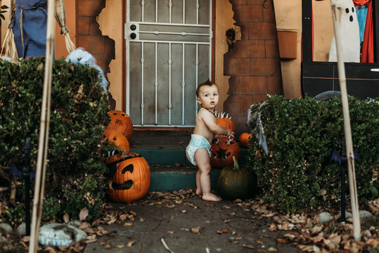 Baby toddler boy in diaper with Halloween decorations during fall