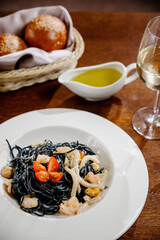 Black spaghetti. Spicy Black seafood pasta with squid with basil on wooden table.