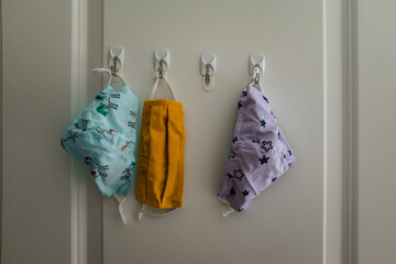 three cloth masks hanging on hooks in closet