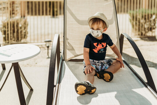 Young toddler boy with mask on sitting by pool in Palm Springs