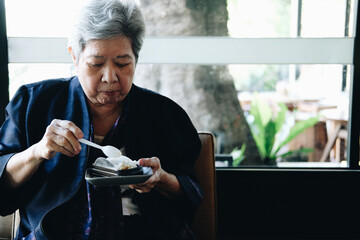 old asian elderly senior elder woman eating cheesecake at restaurant.