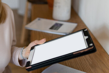 Online digital technology service concept. A girl with blond hair holds a tablet for business in her hands. blank screen mockup