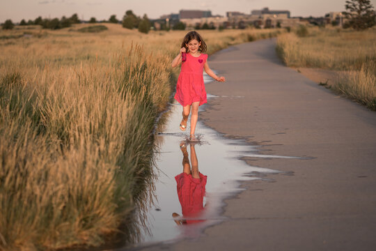 young girl runs through puddle at a neighborhood park holding bubbles