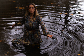 Lady wearing a dress, inside of the water in a autumn day