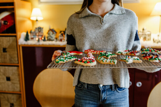 Close up of teen holding tray with decorated holiday cookies