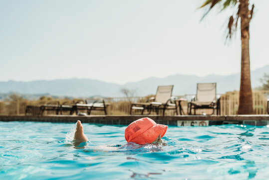 Side angle view of little girl in pink hat swimming in pool