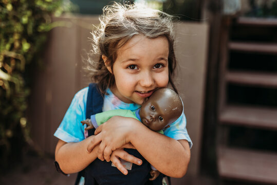 Close up of young girl cuddling with favorite baby doll outside