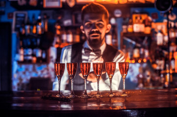 Portrait of bartending pouring fresh alcoholic drink into the glasses in pub