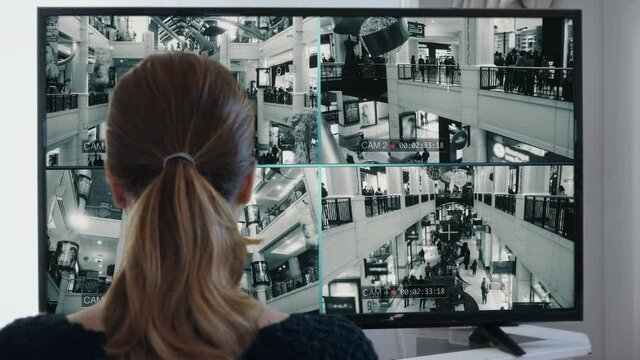 Woman Reviewing Mall Security Cameras CCTV Surveillance People. Woman watching CCTV cameras surveillance system in a crowded shopping mall. Multiscreen monitor.