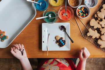 Overhead view of a girl decorating gingerbread cookies at a table