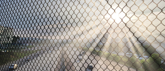 Promienie słoneczne na ogrodzeniu z siatki © michalsen