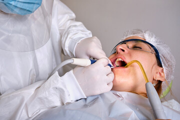 Close up of female dentist drilling tooth to patient