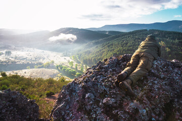 Man watching with the binoculars the bellowing from a rock