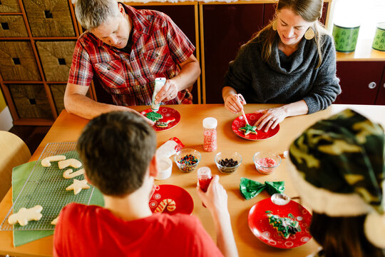 Top View Family Decorating Sugar Cookies Holiday On Table At Home