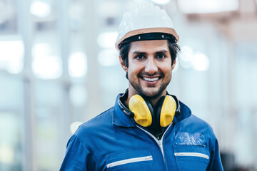 Portrait of smiling handsome industrial engineer worker wearing safety helmet and uniform in modern...