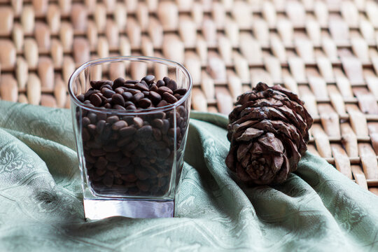 Cone and pine nuts in the glass on the braided surface and green napkin