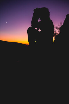 Silhouette of man looking with binoculars at sunset with the moo