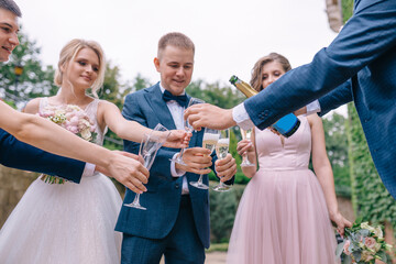 Wedding day. Happy newlyweds are walking with friends, drinking,
