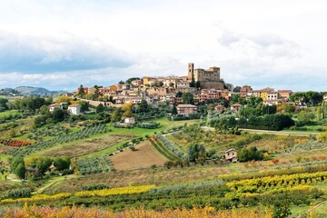 Fototapeta na wymiar Beautiful landscape with small old town on the hill and surrounded by colorful autumn agriculture field against cloudy sky during autumn in Longiano,Province of Forli-Cesena,Italy