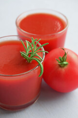 Tomato juice in a glass glass and fresh tomato on a wooden background.